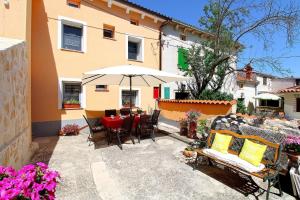 un patio con tavolo, sedie e ombrellone di Ferienwohnung für 6 Personen ca 75 qm in Krnica, Istrien Bucht von Raša a Krnica