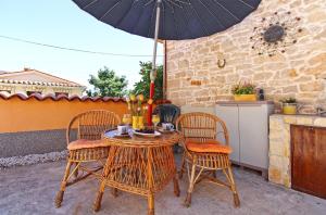een tafel en stoelen met een parasol op een patio bij Ferienwohnung für 6 Personen ca 75 qm in Krnica, Istrien Bucht von Raša in Krnica