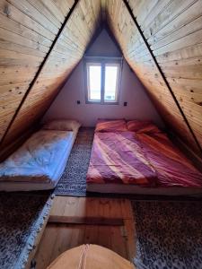 1 dormitorio en el ático con 2 camas en una cabaña de madera en Chata u poľovníka, 