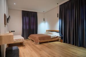 Schlafzimmer mit einem Bett und einem Fenster mit Vorhängen in der Unterkunft Kalpazo Inn Tirana in Tirana