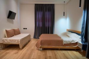 a bedroom with a bed and a couch and a window at Kalpazo Inn Tirana in Tirana