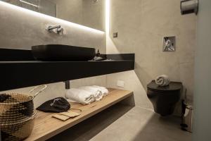 ein Bad mit einem schwarzen Waschbecken und einem WC in der Unterkunft Akrotiri Olympus Luxury Suites - Adults Only in Plaka