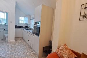 een keuken met witte kasten en een kookplaat oven bij The Tanners Cottage in Hathern +11 foto's