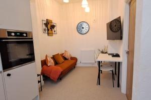 een woonkamer met een bank, een tafel en een klok bij The Tanners Cottage in Hathern