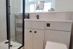 a white bathroom with a sink and a mirror at The Tanners Cottage in Hathern