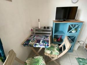 ein Tisch mit Fernseher und ein Schreibtisch mit Computer in der Unterkunft Joli studio vers les thermes, Anatole France -Royat in Royat