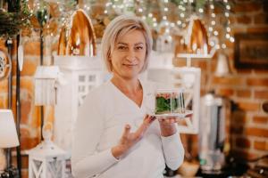 a woman holding a glass bowl of food at Stary Młyn w Brzeźnicy in Brzeźnica