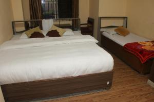 a bedroom with two beds with white sheets at Hotel Opera deluxe in Bharatpur