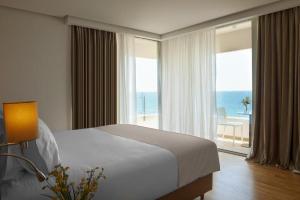 a bedroom with a bed and a view of the ocean at Amare Hotel in Shëngjin