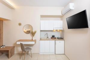 a kitchen with white cabinets and a tv on a wall at Dimitra Central Apartments Chanioti in Hanioti