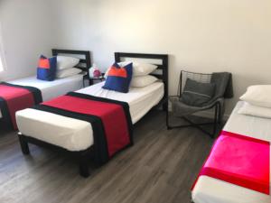 a room with three beds and a chair in it at Modern GuestHouse Ironbound Newark with KITCHEN-FastTrainToNYC-OneStopToAirport in Newark