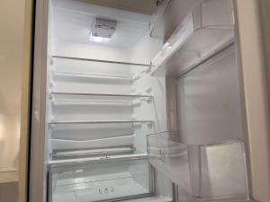 an empty refrigerator with its door open in a kitchen at Bright and Beautiful 2BDR Central London Flat in London