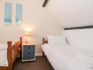 ein Schlafzimmer mit 2 Betten und einem Nachttisch mit einer Lampe in der Unterkunft Grimes Cottage in Staithes