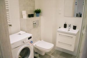 La salle de bains blanche est pourvue de toilettes et d'un lavabo. dans l'établissement Apartament Nero, à Toruń