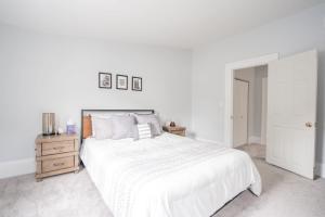 a white bedroom with a white bed and a wooden nightstand at Kentucky Ave - Heart of Mainstrasse in Covington