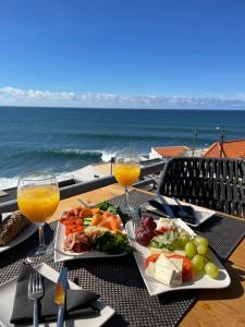 a table with two plates of food and two glasses of orange juice at Boutique Hotel Jardim Do Mar in Jardim do Mar
