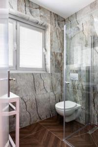 een badkamer met een toilet en een glazen douche bij Sirkin 16 Hotel - Autonomous hotel in Giv‘atayim