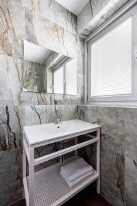 bagno con lavandino bianco e specchio di Sirkin 16 Hotel - Autonomous hotel a Giv‘atayim