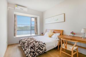 Schlafzimmer mit einem Bett, einem Schreibtisch und einem Fenster in der Unterkunft Xiaojing Bay Haige Hotel in Pingshan