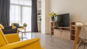 uma sala de estar com televisão e cadeiras amarelas em Cozy apartment in the heart of Tbilisi em Tbilisi