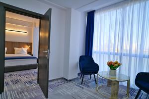 une chambre d'hôtel avec un lit, une table et des chaises dans l'établissement Hotel Sir Royal, à Bucarest