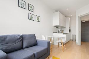 One Bedroom Serviced Apartments in Harrow في Pinner: غرفة معيشة مع أريكة زرقاء ومطبخ
