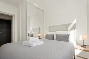 a white bedroom with a large white bed with two lamps at One Bedroom Serviced Apartments in Harrow in Pinner