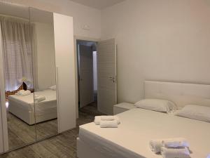 a white bedroom with two beds and a mirror at My Art home in Salerno