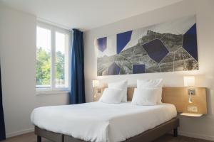 - une chambre avec un grand lit blanc orné d'une peinture murale dans l'établissement Brit Hotel Mâcon Centre Gare, à Mâcon