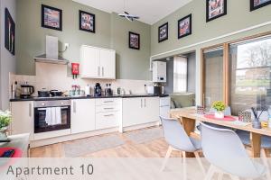 a kitchen with white cabinets and a table and chairs at CADeS Dudley in Dudley