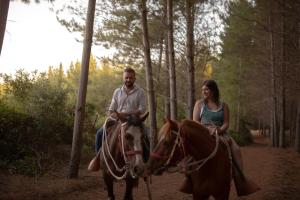 un hombre y una mujer montando un caballo en el bosque en Glamping, escapada en la naturaleza en San Clemente