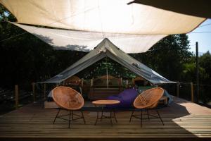 dwa krzesła i namiot na drewnianym tarasie w obiekcie Glamping, escapada en la naturaleza w mieście San Clemente