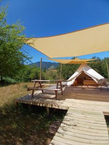 a large yellow tent with a bench and a table at Glamping, escapada en la naturaleza in San Clemente