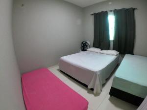 a bedroom with two beds and a pink rug at Casa Temporada Atalaia in Luis Correia