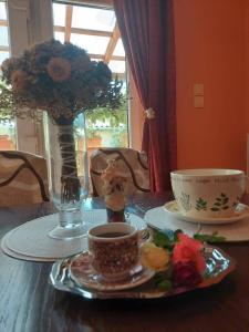 uma mesa com uma chávena de café e um vaso com flores em Schönes Ferienhaus mit Pool in ruhiger Lage em Balatonszentgyörgy