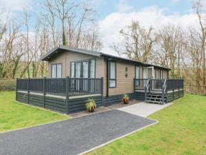 a tiny house with a porch and a fence at 18 Manleigh Park in Ilfracombe