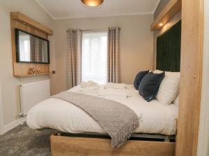 a bedroom with a bed with white sheets and a window at 18 Manleigh Park in Ilfracombe