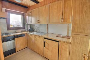 a kitchen with wooden cabinets and a sink and a window at Haute-Nendaz in Nendaz