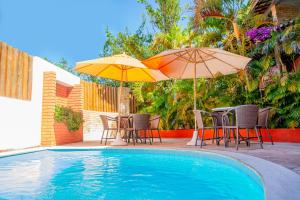 dos sombrillas, mesas y sillas junto a una piscina en Garbos Soleil Hotel, en Natal