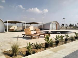 two wooden chairs sitting in a patio with a fountain at Desert Breeze in Al Ḩamrānīyah