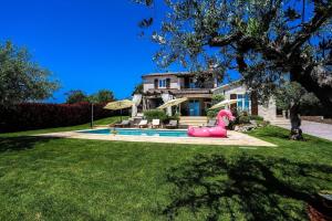 a house with a pink inflatable pig in front of a pool at Villa Elizabet bei Porec mit Pool in Babići