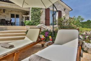 a patio with two chairs and an umbrella at Villa Elizabet bei Porec mit Pool in Babići