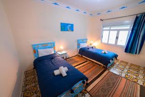 a bedroom with two beds with blue sheets and a teddy bear at Casa Voyager 'secret garden terrace' in Chefchaouen