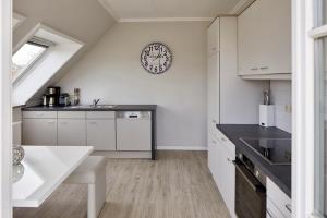 a kitchen with white cabinets and a clock on the wall at Techts Strandhaus in Timmendorfer Strand