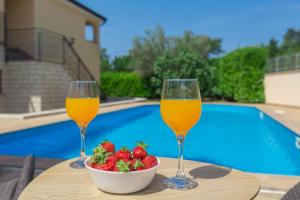 zwei Gläser Wein und Erdbeeren auf einem Tisch in der Nähe eines Pools in der Unterkunft Ferienwohnung mit Pool, 200m vom Strand, ruhige Lage in Poreč