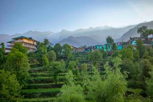 a village on a hill with mountains in the background at Hotel Bob's N Barley in Dharamshala