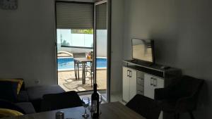 ein Wohnzimmer mit Fernseher und Tisch mit Stühlen in der Unterkunft THREE FLOOR Deluxe Pool Apartments in Novalja
