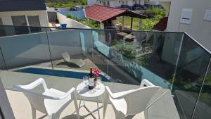 ein weißer Tisch und Stühle auf einem Balkon in der Unterkunft THREE FLOOR Deluxe Pool Apartments in Novalja