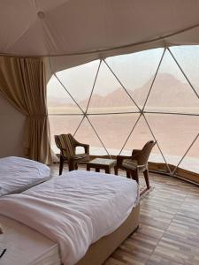 a bedroom with a bed and two chairs in a tent at Wadi Rum palace in Wadi Rum