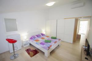 a white bedroom with a bed and a red stool at Ferienwohnung für 6 Personen ca 100 qm in Pula, Istrien Istrische Riviera in Pula